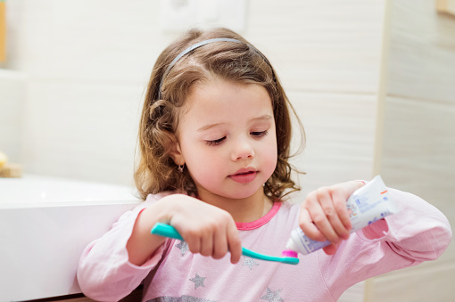 Child putting toothpaste on a toothbrush at Uptown Family Dental in Portland, OR