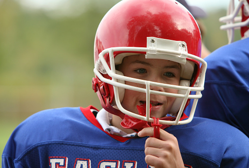Kid wearing football gear and holding sports mouthguard