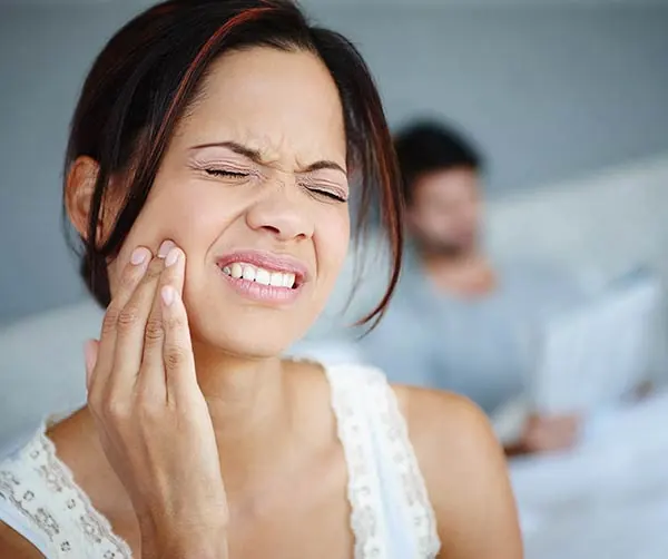 woman holding her mouth due to tooth pain